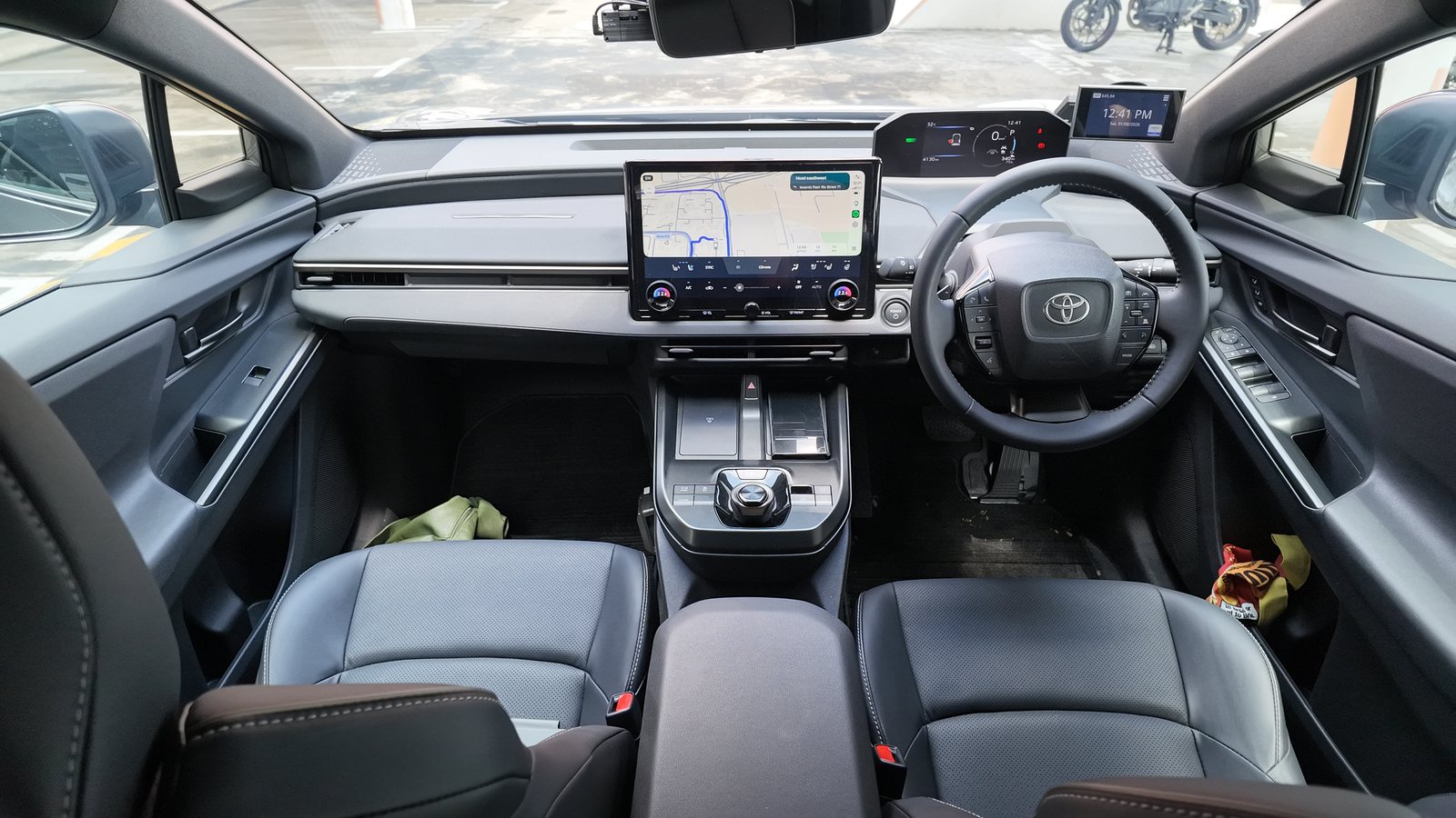 Toyota bZ4X cabin viewed from the rear seats, showing an all-black interior, the 14-inch screen and the dial gear selector