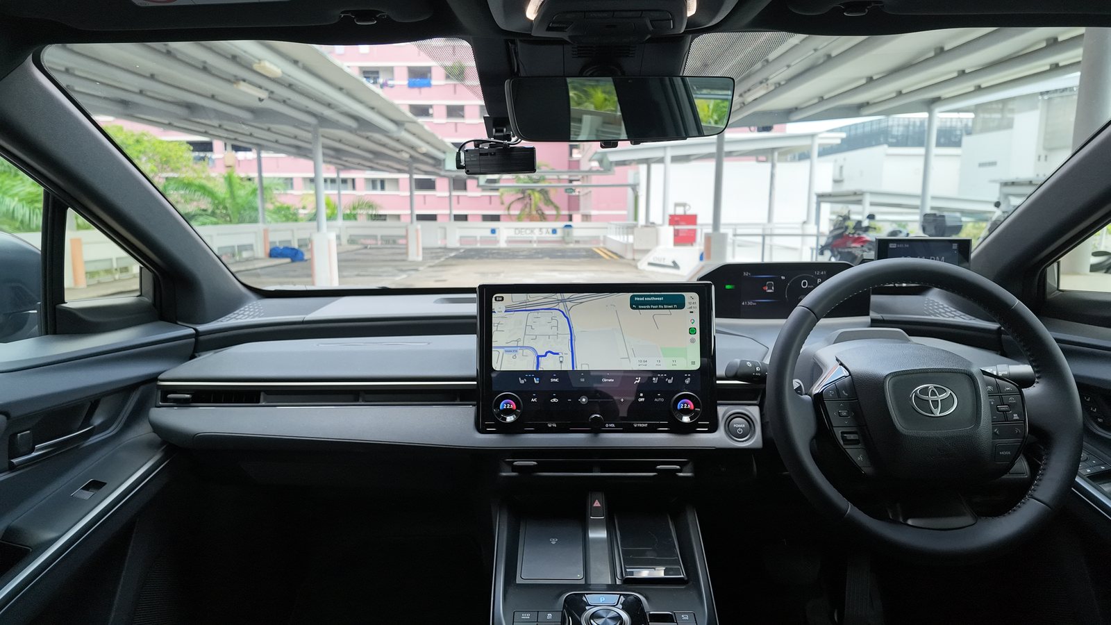 Toyota bZ4X dashboard from the front passenger side, showing the 14-inch screen, the small steering wheel and the instrument display above it