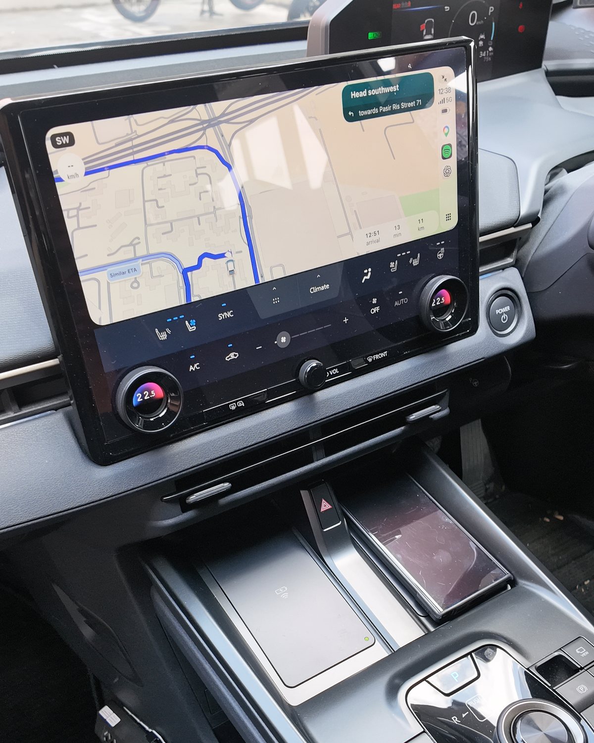 Toyota bZ4X 14-inch touchscreen with CarPlay navigation, physical climate dials below it, the power button and two wireless charging pads on the console