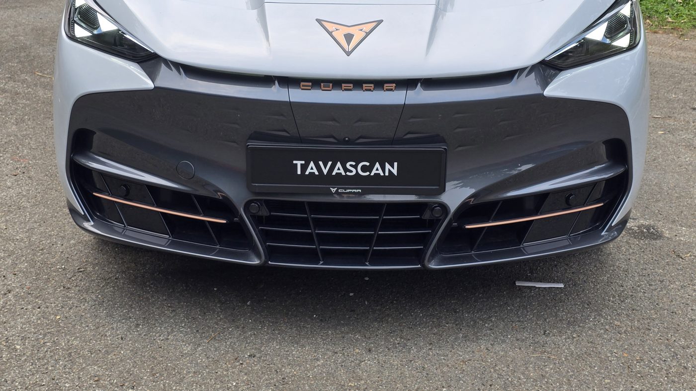 Cupra Tavascan head-on, showing the triangular headlight elements, the copper trim in the lower bumper and the TAVASCAN plate