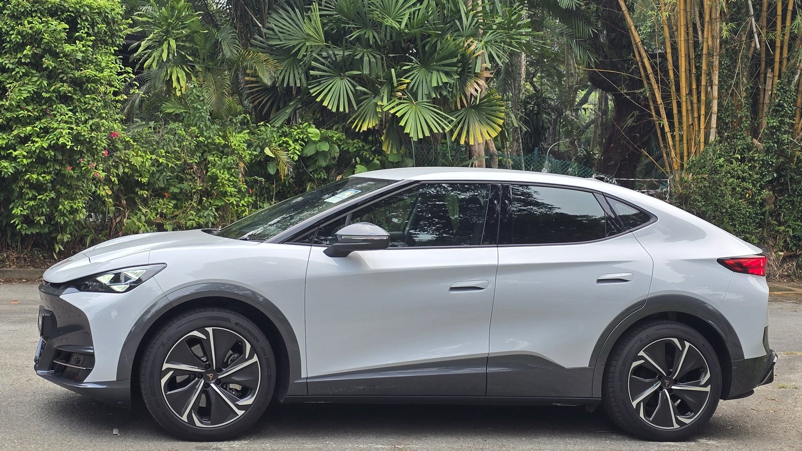 White Silver Cupra Tavascan Endurance, side profile in a tree-lined carpark in Singapore