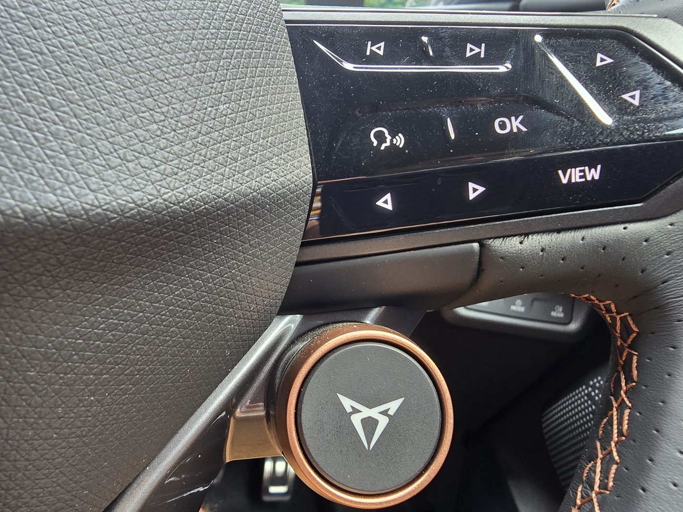 Cupra Tavascan steering wheel spoke with the round copper Cupra mode button and touch controls above it