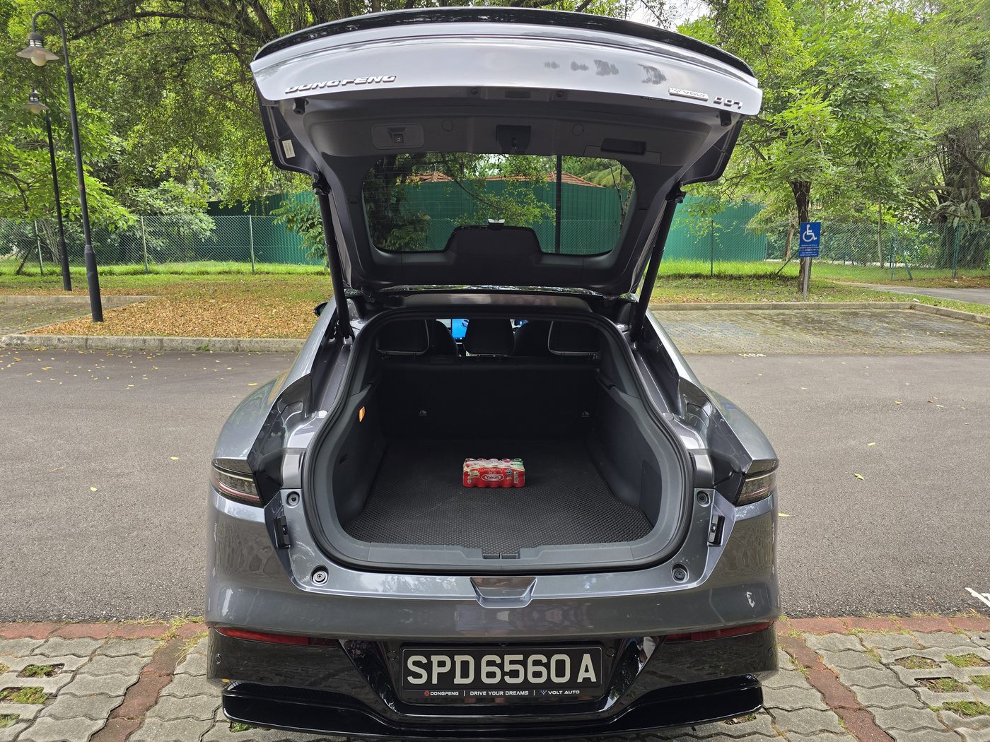 Open liftback of the Dongfeng 007 showing the flat 452-litre boot with a pack of Yakult for scale