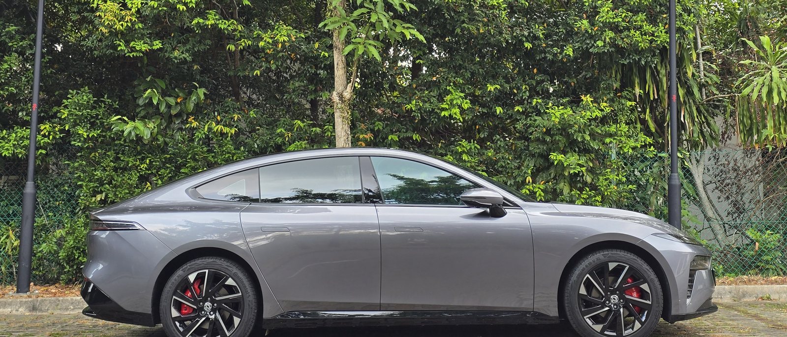 Dongfeng 007 Premium in Eclipse Grey, side profile against dense greenery in Singapore