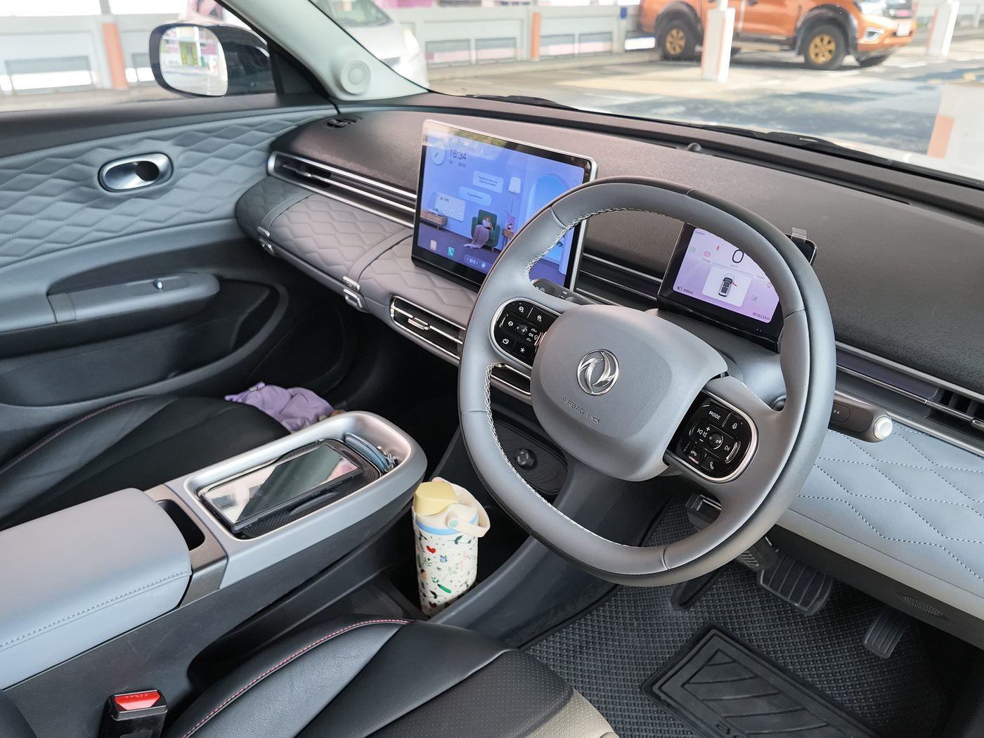 Driver's side of the Dongfeng Box R cabin: quilted door, small steering wheel, 5-inch driver display and the 12.8-inch screen showing the living room