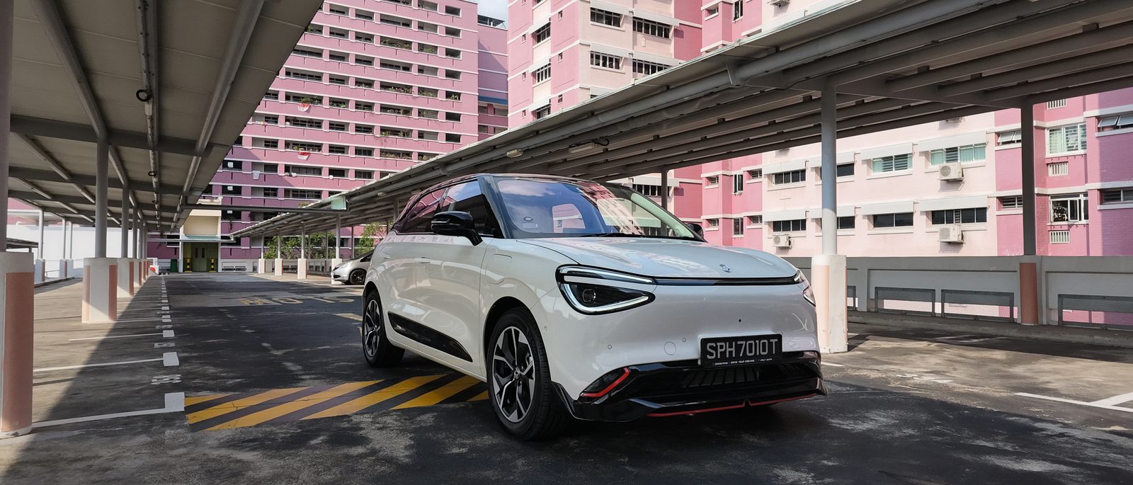 Dongfeng Box R in Twilight White with a black contrast roof, front three-quarter view in a Singapore HDB multi-storey car park