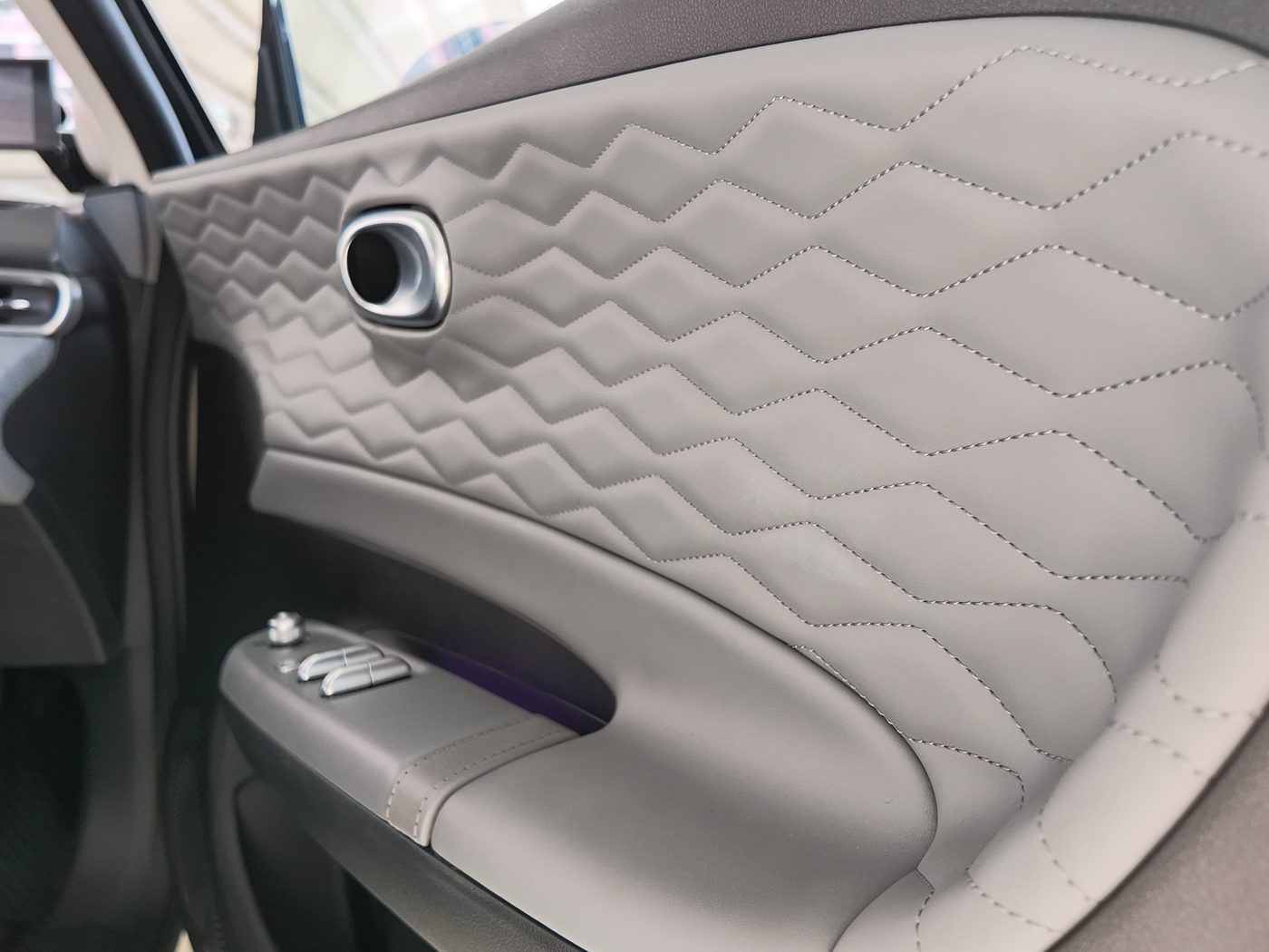 Close-up of the quilted grey door trim in the Dongfeng Box R, with the door handle and window switches
