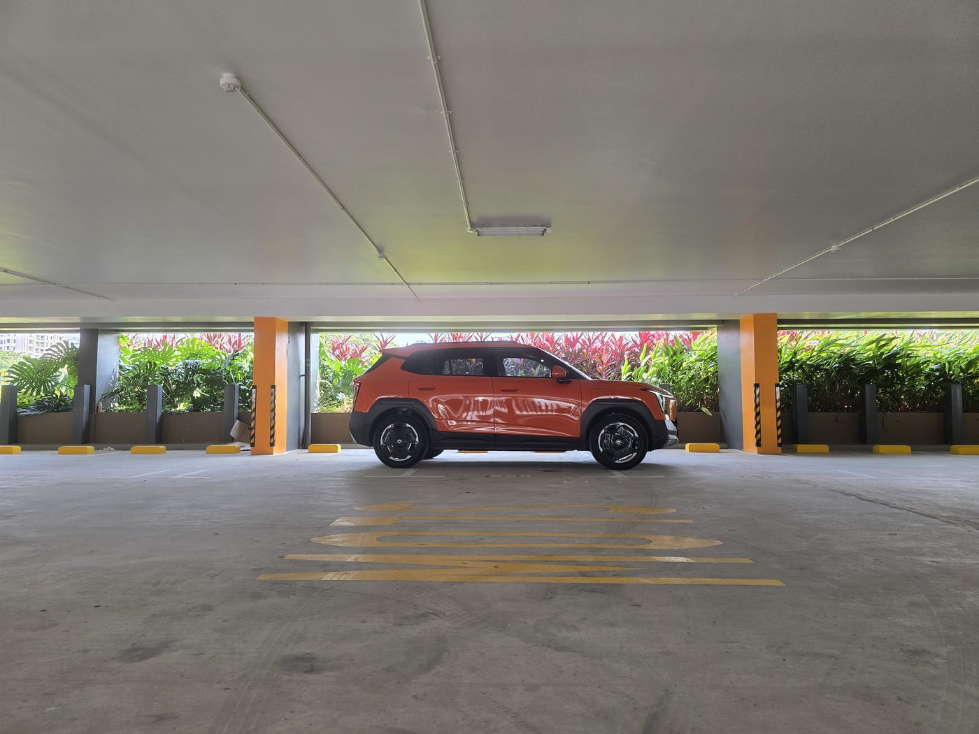Side profile of the Dongfeng Vigo in Canyon Orange parked against tropical greenery in Singapore