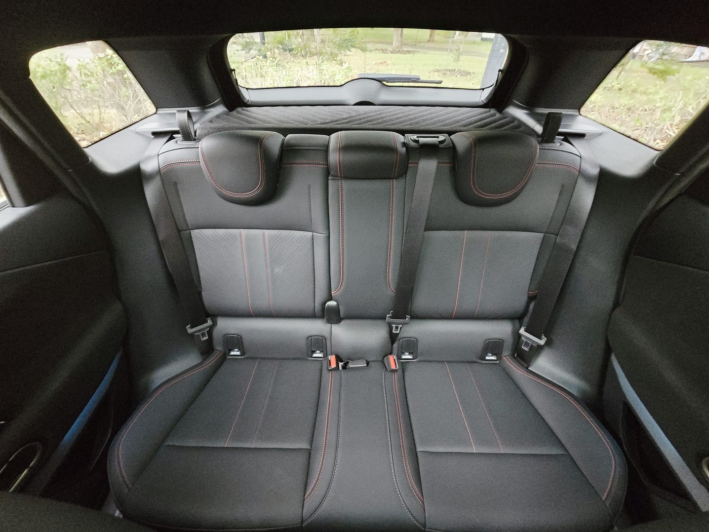 The rear bench of the MINI JCW Aceman E in black JCW cord upholstery, viewed through the open door