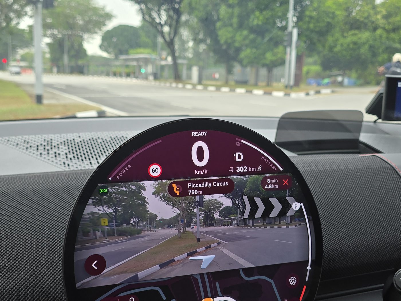 The MINI JCW Aceman E round display in Vivid mode, running the augmented reality navigation over a live camera view of the road