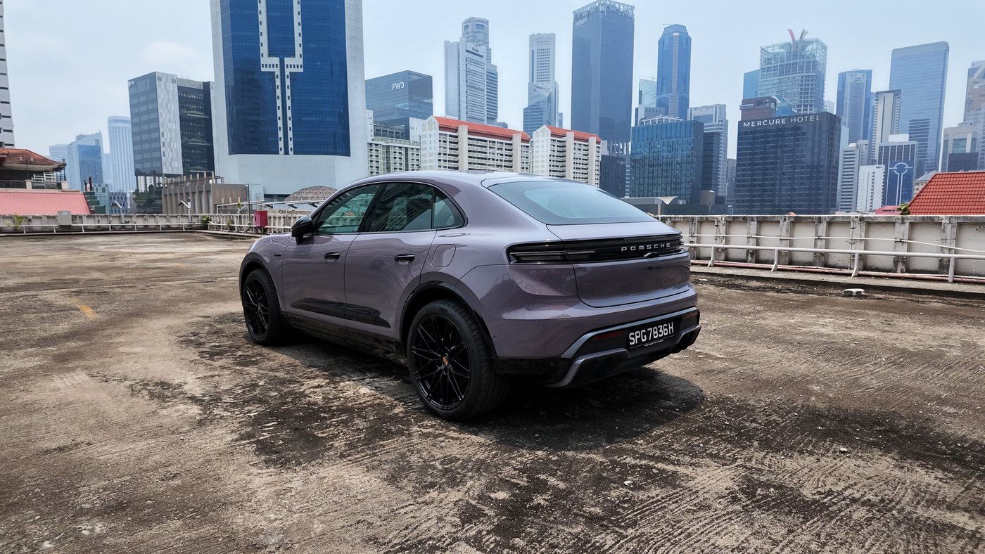 Porsche Macan Electric rear three-quarter view on a rooftop carpark against the Singapore CBD skyline