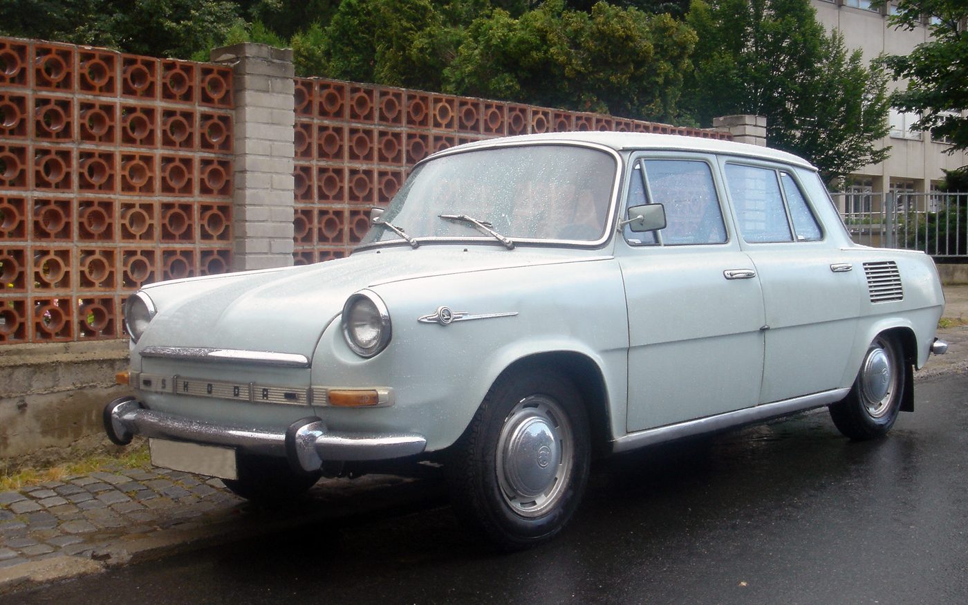 A pale blue Škoda 1000 MB parked by a wall