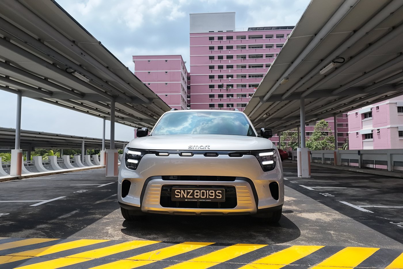 smart #5 Pro head-on between the carpark deck columns, pink HDB block behind