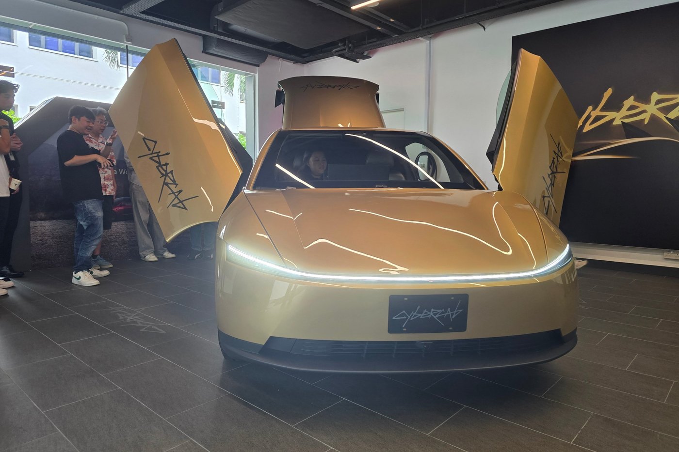 Tesla Cybercab head-on at the Tesla Experience Centre in Toa Payoh, both butterfly doors and the hatch raised, light bar lit