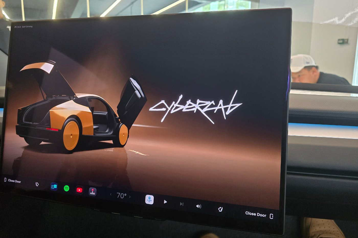 The Tesla Cybercab centre screen with PRND and Self-Driving in the corner, the app dock and Close Door buttons