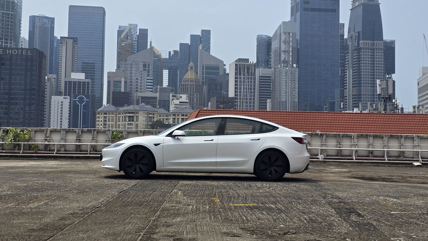 White Tesla Model 3 in profile against the Singapore city skyline