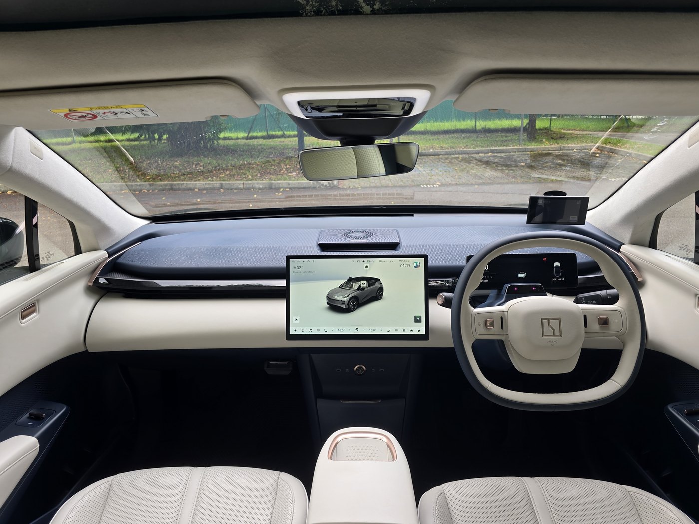 Zeekr X Urban cabin from the back seat, showing the navy dashboard, cream seats and steering wheel, and the 14.6-inch centre screen