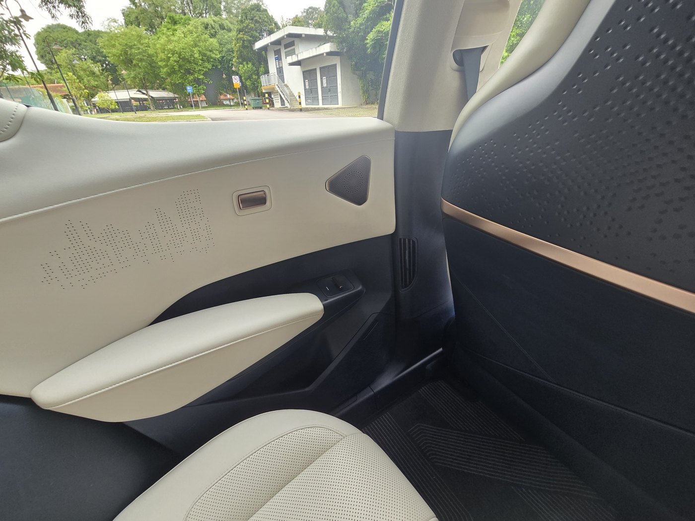 Zeekr X Urban front door card in cream with a perforated pattern, navy lower section and rose-gold trim on the dash